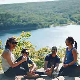 Friends Sitting Atop Bluff Overlooking Lake