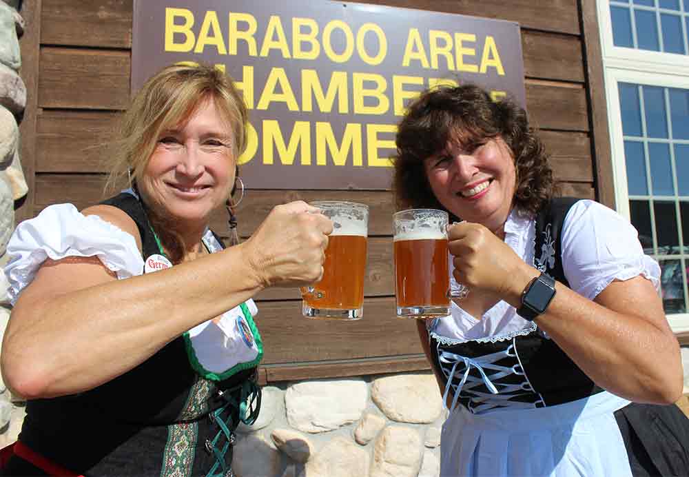 Two Women In Dirndls Sharing Beers